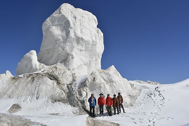 Wentao Hu (Mitte) mit seinen Chinesischen Forscherkollegen neben einem der Eisblöcke, die sich aus dem Gletscher gelöst hatten. Foto: Wentao Hu